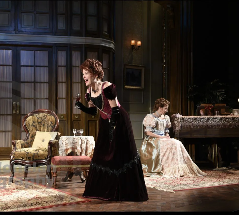 stage with a woman singing, playing an ivory piano while another woman sits at the other side of it.